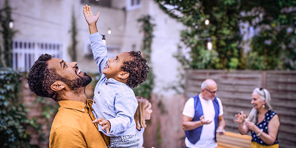 Father lifting child to fairy lights